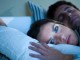 Femme allongée insomniaque à côté de son mari